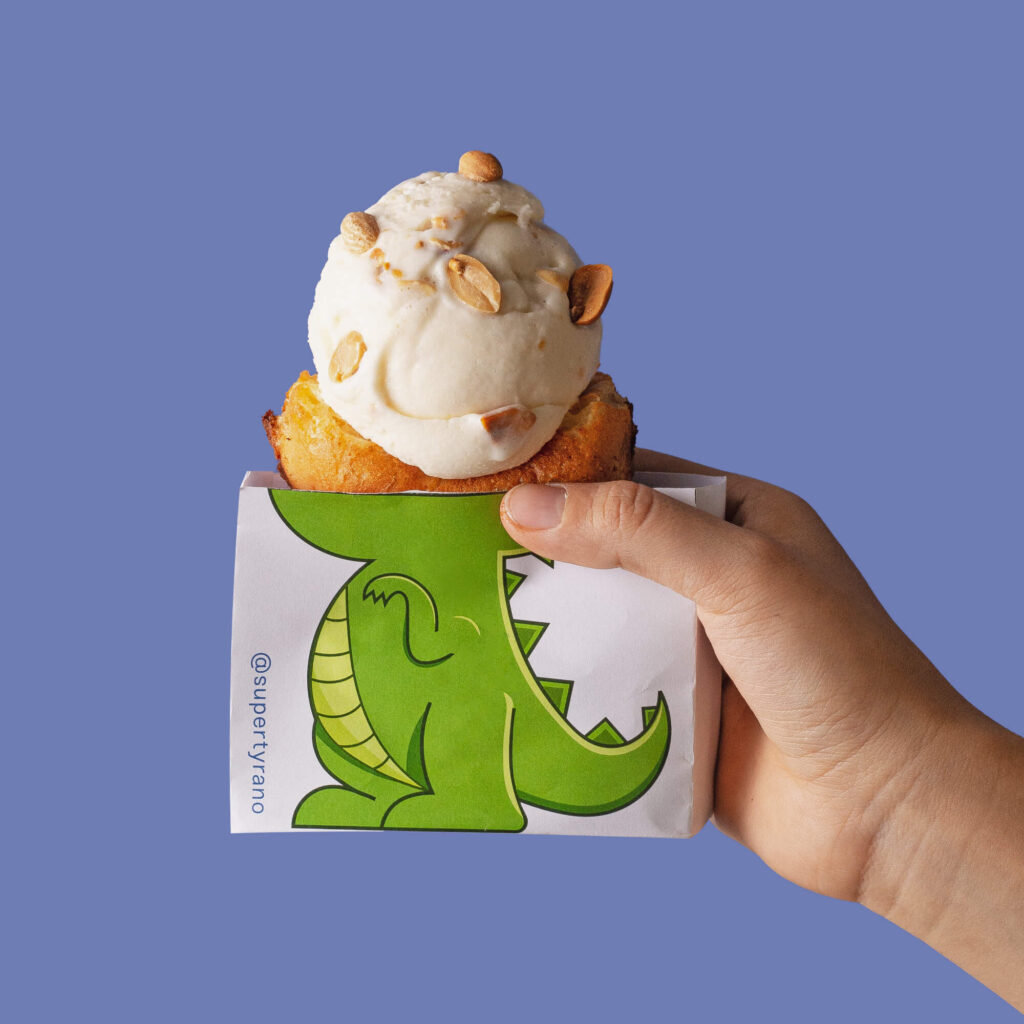 Helado con almendras tostadas en un dinocono de waffle sobre un fondo azul.